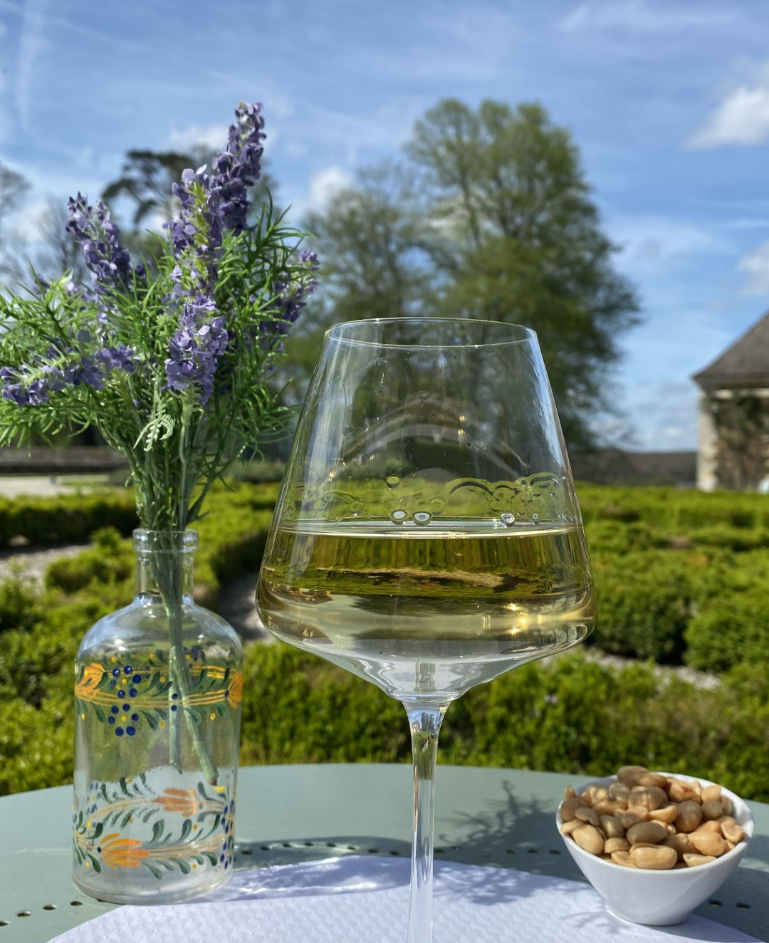 alt="Apéritif en terrasse avec cacahuètes et verre de vin blanc"