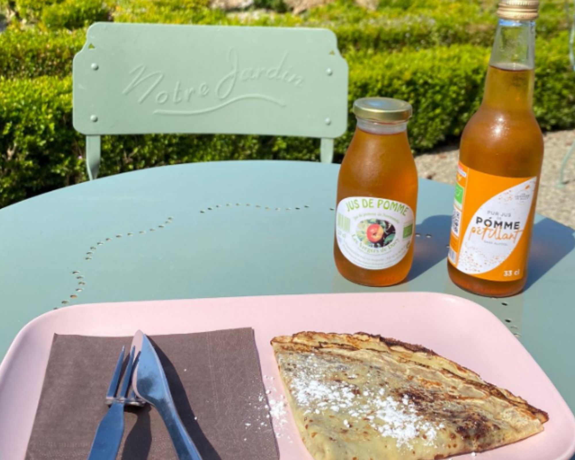 alt="Crêpe maison et jus de pomme sur une des tables de la terrasse du Château"