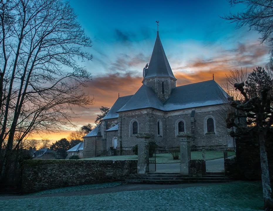 alt="Église du village de Balleroy, architecture normande mise en valeur par la lumière hivernale."