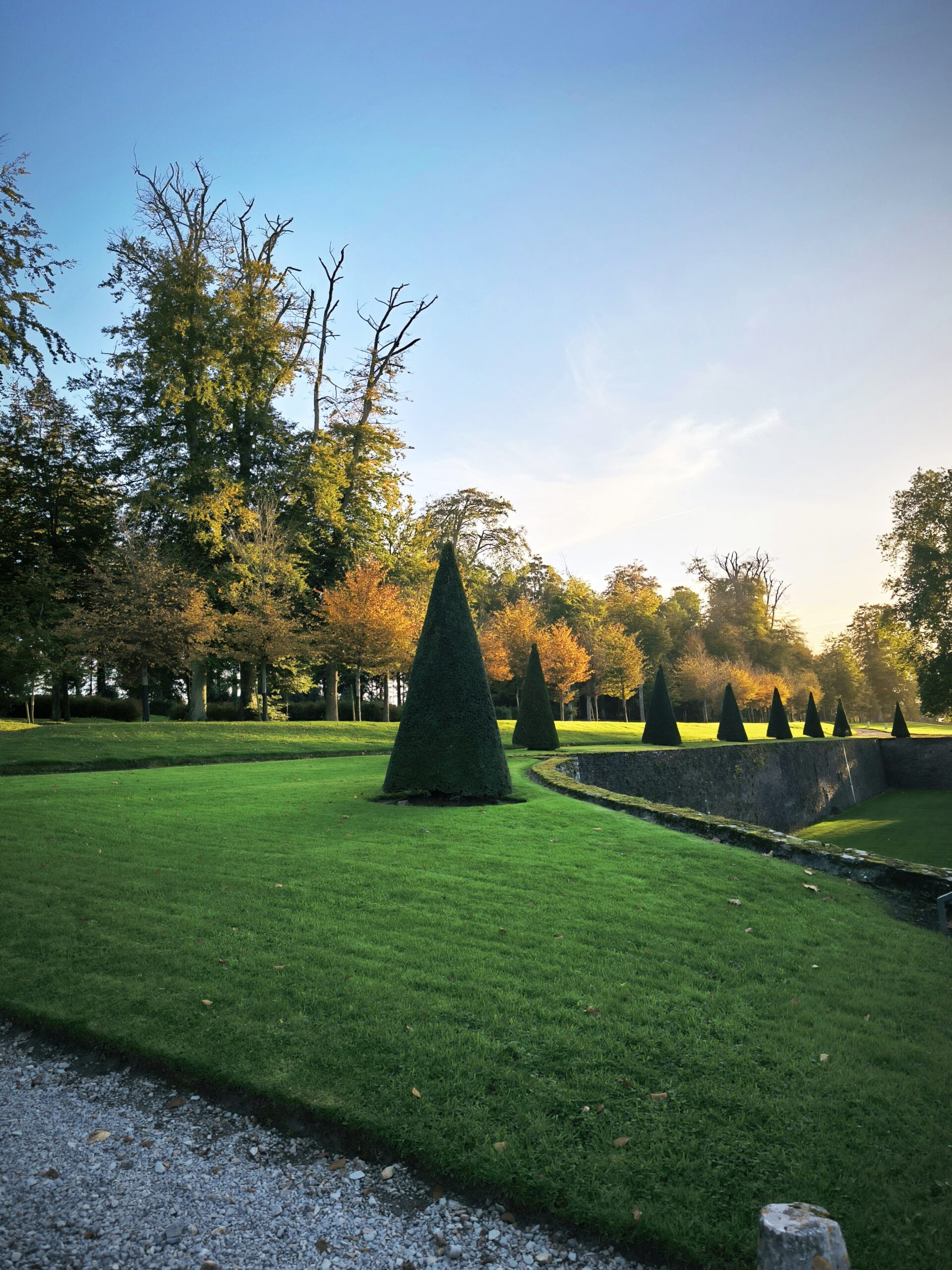 alt="Contraste saisissant entre l’herbe verdoyante et les couleurs chaudes de l’automne dans le parc du Château de Balleroy"