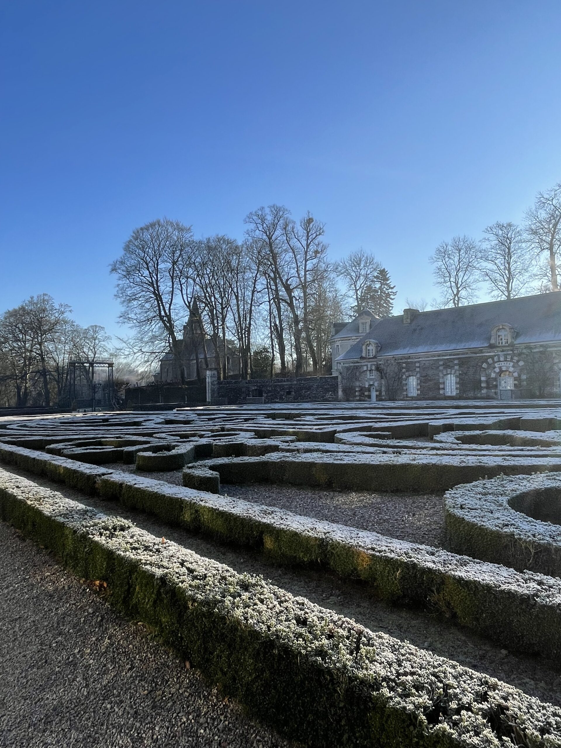 alt="Les jardins à la française recouverts de givre, par une matinée d'hiver"