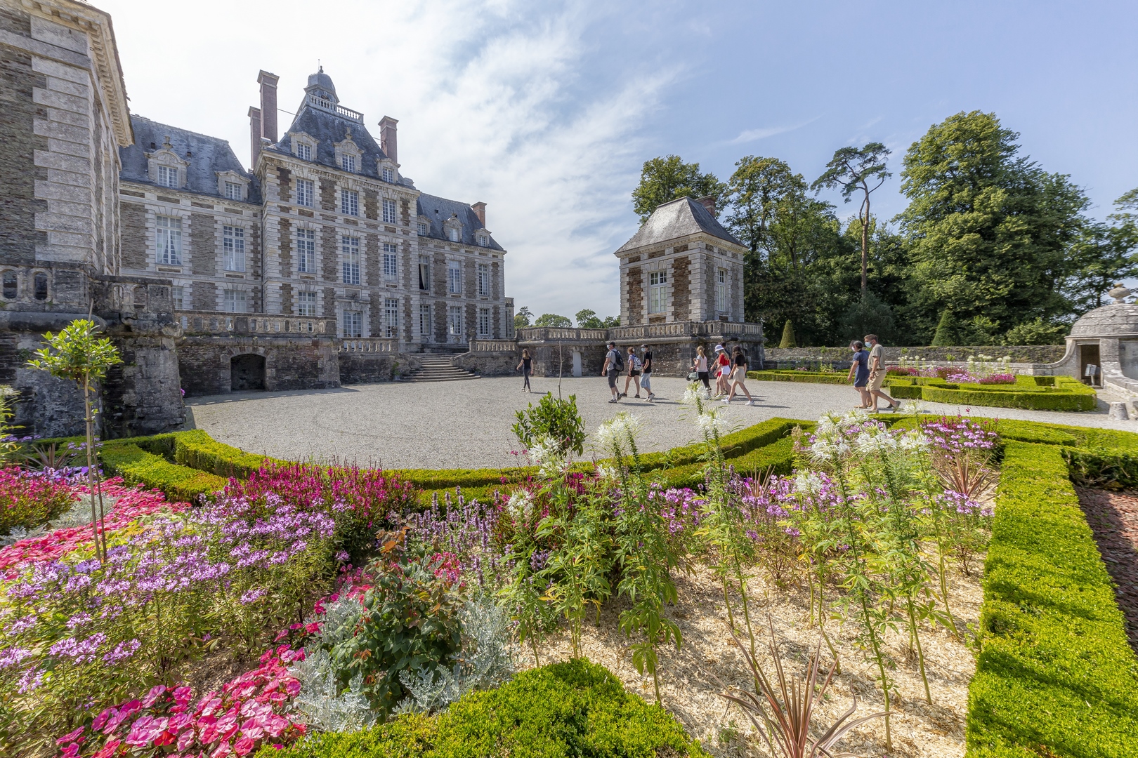 alt="Vue latérale du Château avec buis fleuris au premier plan"